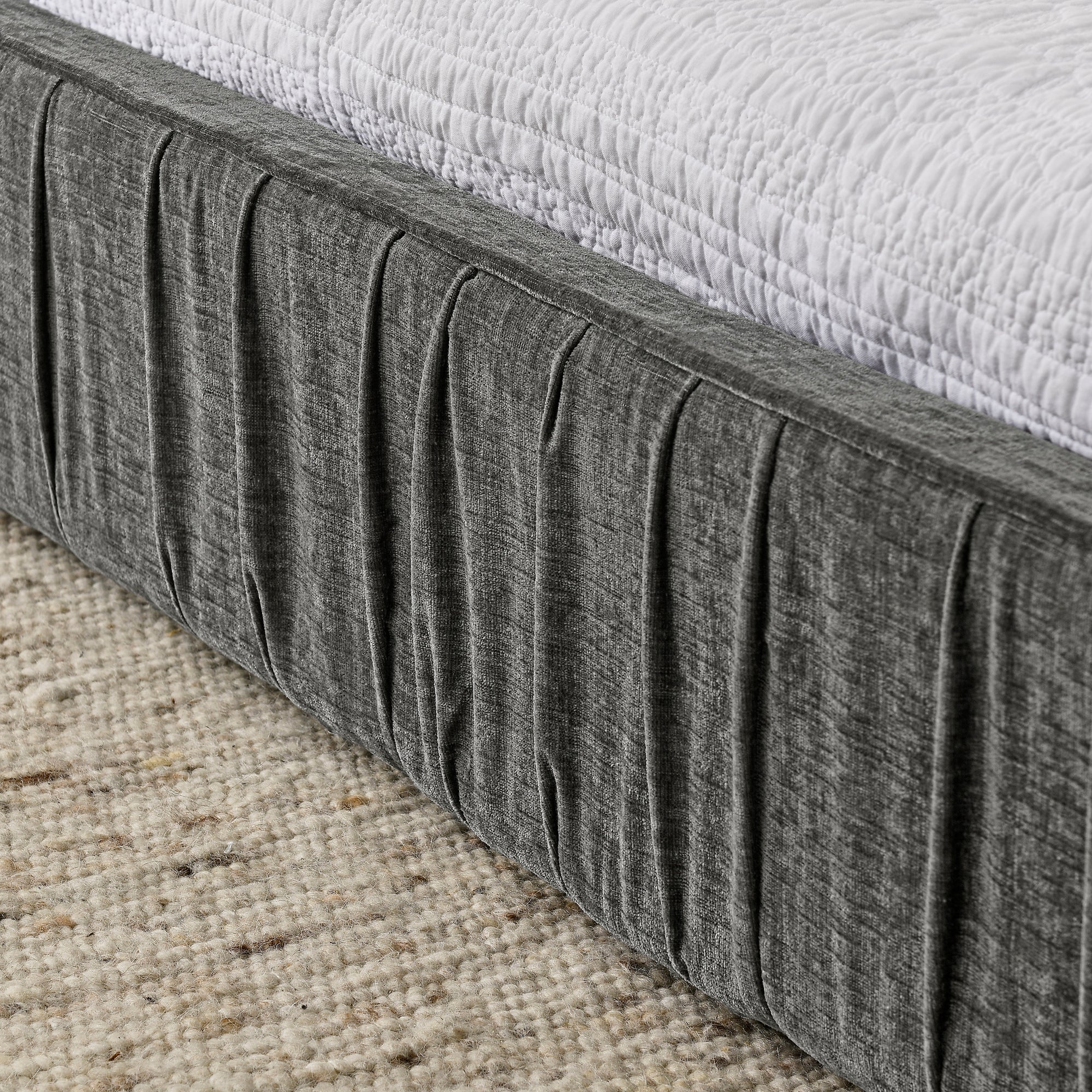 The large grey padded bed frame is designed with Chenille fabric
